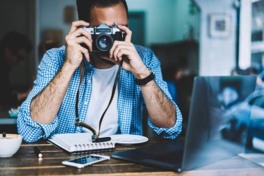 Resim düzenleme, fotoğraf görüntü üzerinde vintage fotoğraf makinesi alarak kahve dükkanında dinlenme hobi vakit zevk hipster adam için netbook ile masada oturan Kafe'nin yetenekli erkek fotoğrafçı