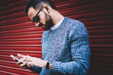 Yakışıklı adam açık havada, hipster adam bloglama sosyal ağlar üzerinde kentsel ayarları hücresel harcama boş dosya yükleme ayakta şehirde café arama için smartphone uygulama kullanarak