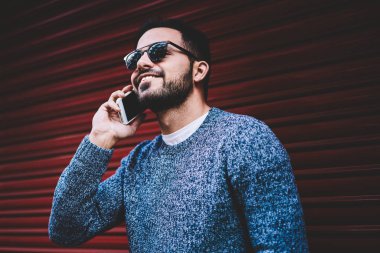Cep telefonu ucuz tarifs gezici ayakta trendy kıyafeti telefon görüşmesi ile bağlantı memnun olan erkek kişi kentsel ayarları kullanarak üzerinde konuşurken gülümseyen genç hipster adam