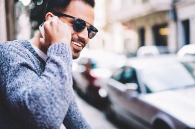 Hipster adam arkadaş telefon görüşmesi ucuz tarifeler kullanarak dolaşım duymaktan mutlu gülümseyerek, neşeli genç adam açık havada vakit telefon konuşmayı mobil bağlantı ile memnun