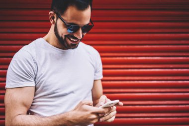 Neşeli adam açık havada, eğlence keyfini smartphone üzerinden geri göndermeye arkadaşım hipster adam memnun üstünde hareket eden telefon Caddesi üzerinde yüklü uygulama ile gülümseyen mesaj söyleyeceğiiçin çok mutlu