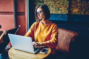 Dizüstü cihaz serbest çalışma gözlük içinde akıllı konsantre kadın metin yazarı bağlı 4g yüksek hızlı internet kafede. Zeki kadın tasarımcı netbook, yeni grafik geliştirme