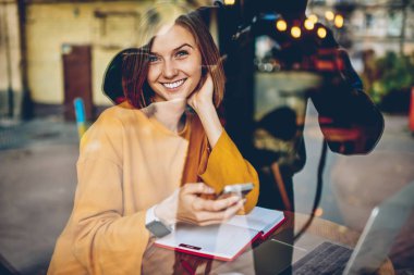 Yarım uzunluk portre mutlu güzel Blogger kendi website.positive öğrenci güncelleştirme uygulama kameraya gülümseyen smartphone cep telefonu ile son yayında altında takipçileri iyi yorum aldı