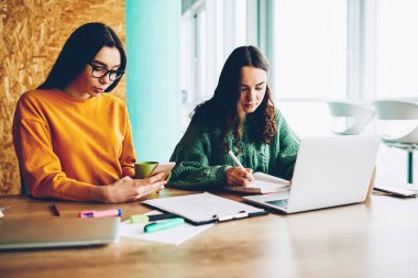 Zeki öğrenci arkadaşıyla seminer yazma planı not defterinde eğitim ve bilgi smartphone cep telefonu ile ortak proje masaüstü dizüstü bilgisayar ile oturup için Web sitelerinde arama için hazırlanıyor