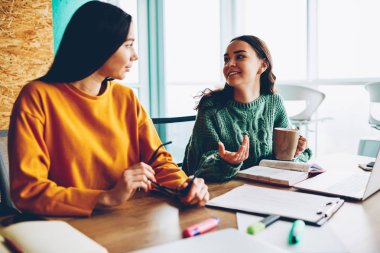 İki başarılı öğrenci zevk lezzetli çay molası sırasında birbirleriyle iletişim kurmak. Comon oturma yazıhane proje eğitim için yeni fikirler söz giyim tasarımcıları giymiş