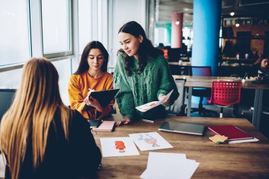 Yetenekli öğrencilerin birbirleri ile yeni oluşturmak için fikirleri hakkında iletişim Üniversitesi'nde beyin fırtınası sırasında çizimler tasarlayın. Birlikte kendi moda katalog Office geliştirmeye çalışan genç kadınlar