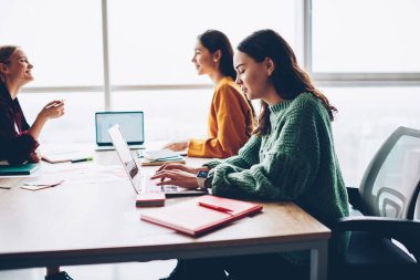 Klavye masaüstü tasarım projesi için fikirler tartışırken meslektaşları wich birlikte oturan kablosuz internet'e bağlı modern netbook aygıt bilgileri yazarak dalgın kadın metin yazarı