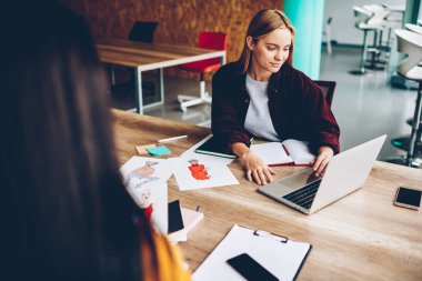 Yüksek olarak bağlı dizüstü bilgisayar, grafik geliştirme yaratıcı bonde tasarımcı çalışma hızda internet. Genç kadın masaüstü netbook ve çizimler ile oturan web sitelerinde yeni fikirler arıyor