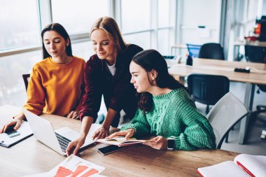 Modern laptop tasarım sunum oluşturma konusunda işbirliği dalgın genç kadınlar için 4 g bağlı Office Internet. Masaüstü netbook ile oturan moda çizimler üzerinde yaratıcı öğrenciler teamworking
