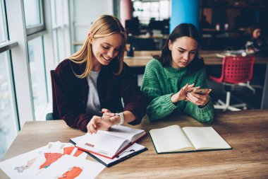 Teamworking ise modern smartwatch zamanında kontrol profil ahşap masaüstü tasarım çizimler ve bloknot moda Studio ile oturan smartphone aygıt üzerinde güncelleştirme meslektaşım wich ile pozitif öğrenci