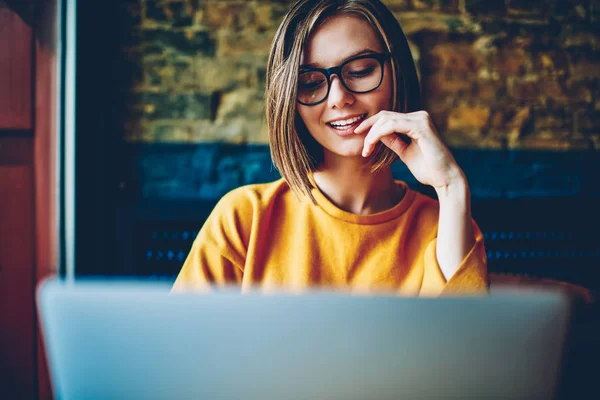 眼鏡とコーヒー ショップに座っている無料の高速インターネット接続を使用して近代的なコンピューター上の友人と社会的ネットワークのオンライン チャット ショート陽気な魅力的な女子学生 — ストック写真