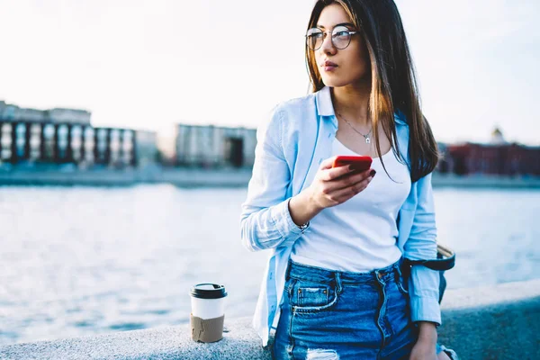 休んでいる思いやりのある若い女性 先に立って見てネットワークのブログのコピー スペース屋外に時間を費やすモバイル経由でメッセージを送信するカジュアルな服装で魅力的な女性 — ストック写真