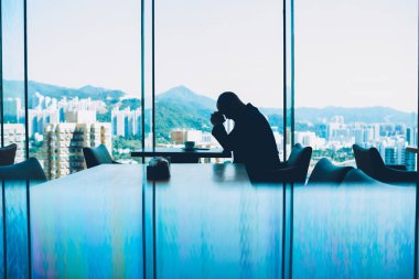 Zor iş günü ve başarısız iş projesi ile güzel bir akşam metropolis manzara ile modern kafeterya kahve fincan masada oturan depresif erkek gurur CEO'su yorgun