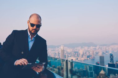 Finansal haber modern binanın çatı terasta metropolis manzaralı dinlenme dijital tablet ile internet web sitesinde gezinirken şık güneş gözlüğü emin icra müdürü