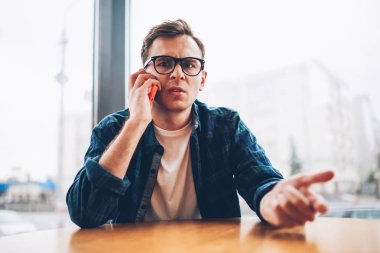 Yarım uzunluk portre serin gözlük ile sokulgan yolu ile telefon iletişim durulması erkek öğrencinin 4 g için bağlı. Genç adam kapalı cep konuşurken kameraya bakan şaşırttı