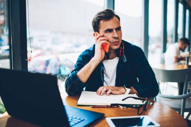Genç erkek kişi smartphone iletişim iyi kahve dükkanında otururken kablosuz internet'e bağlı. Mobil meslektaşı ile kapalı konuşmayı profesyonel serbest meslek