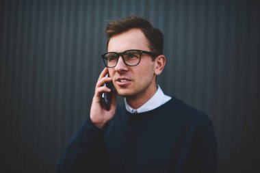 Genç yakışıklı adam cool gözlük ile sokulgan yolu ile uygulama için 4 g bağlı smartphone cep telefonu ile iletişim içinde görüntüsünü kapatın. İyi görünümlü hipster adam cep telefonunuzun yürüyüş sırasında Sokağı'nda bahsediyoruz.