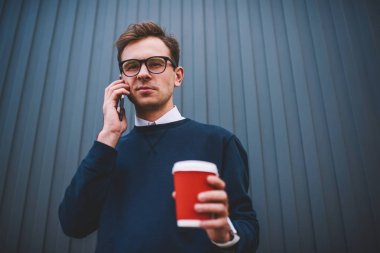 Portre pozitif gencin serin gözlük ile sokulgan yolu ile açık havada gezinme sırasında hücresel uygulama iletişim içinde. Street serbest zaman tadını çıkarırken kameraya bakarak mutlu erkek blogger