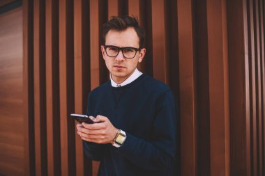 Yarım uzunluk portre serin gözlük ile sokulgan yolu ile smartphone ve 4 g olarak sosyal ağlar sohbet kendine güvenen insanın. Yakışıklı hipster adam telefonla e-posta iletisi gönderirken kameraya bakıyor