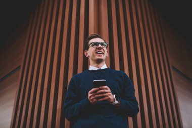 Son moda gözlük sosyal ağ takipçileri ile yaz yürüyüş sırasında sohbet sırasında eğlenmek genç yakışıklı neşeli adam. Mutlu hippi herif iyi bir ruh hali ile kentsel ayarı boş zaman zaman harcama