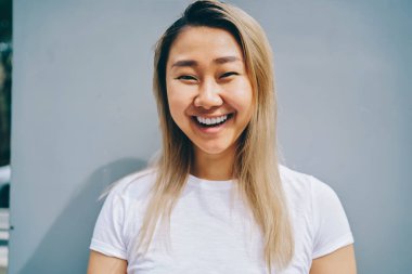 Üzerinde mavi arka plan, neşeli sarışın Asyalı kadın gömlek markası veya kameraya bakarak etiket için kopya alanı ile poz gülüyor serbest zaman sırasında eğlenmek şirin Asyalı kız portresi yarım uzunluk