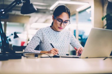 Accountings yapma ve dizüstü bilgisayar, netbook vasıl okul sırası oturan kullanarak üniversite kitaplığında sınavlarına hazırlanıyor kız öğrenci üzerinden bilgi analiz proje üzerinde Eyewear konsantre kadın