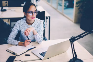 Genç esmer işkadını Web sayfasında laptop netbook ofis planlama proje hazırlama iç online araştırma yapma masaüstü, yetenekli kadın oturan mali haber okuma