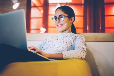 Gülümseyen kadın serbest serbest zaman haber bloglama sosyal ağlar netbook kullanarak okuma sırasında dinlenme rahat coworking iç, kadın öğrenci üzerinde çalışan dizüstü bilgisayar video izlerken Eyewear