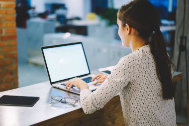 Arkadan görünüşü kadın çalışan dizüstü bilgisayarla iletişim sahte ekran indirme Multimedya ve arama arama bilgilerinizi online yazarak; netbook kullanarak office çalışma yerinde oturan kadın