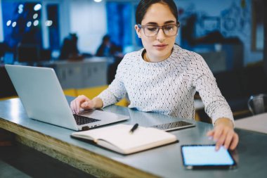 Modern teknolojiler, iş kadını ofiste oturmuş boş tablet monitör gelir mesaj okuma kullanarak masaüstü çalışan touchpad üzerinde uygulama yükleme Eyewear yetenekli kadın Tasarımcısı