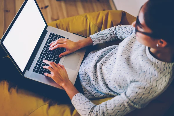 女性フリーランサー距離コワーキング オフィスで仕事をしている Web ページ上の文書をキーボード入力画面モックアップのネットブックを使用してラップトップ コンピューターをオンラインで情報を検索で入力する女性のトップ ビュー — ストック写真