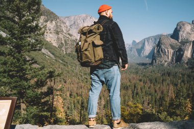 Hafta sonları macera, tepe en iyi destinatination için getting manzara bakarak duran erkek yolculuk tutkusu sırasında Yosemite Milli Parkı ile vahşi topraklarda keşfetmek turistik sırt çantası ile hipster adam