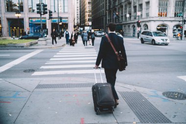 Arkadan görünüşü işadamı yürüme şehir geçişi trafik kavşak üzerinde zebra, erkek girişimci iş için seyahat sırasında caddenin üzerinde Bagaj okşayarak ile formal giyim çanta