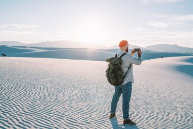 Akıllı telefon, video ile horizo kum tepelerine beyaz kumları milli park içinde nefes kesen panoramik çekim sırt çantası ile erkek gezgin resim yapma çöl ortamı keşfetmek hipster adam yolculuk tutkusu