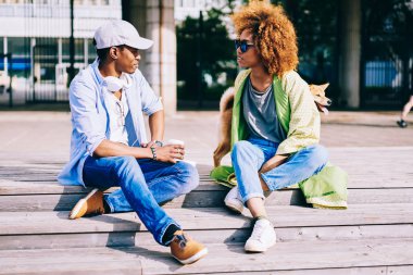 Trendy giyim birbirlerine kare akita Inu yürüyen merdivende oturup konuşmak koyu tenli en iyi arkadaş ile evde beslenen hayvan, bahar güneşli gün boyunca sokakta dinlenme aşık Afro Amerikan çift