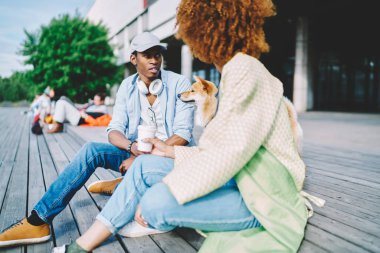 Kahve harcama trendily giyinmiş hipster arkadaşları birlikte yürüyen akita Inu köpek şehir sokakta, koyu tenli adam kıvırcık saçlı kız arkadaşıyla dinleniyor zorla ve Meydanı'nda oturan konuşma hafta sonu evde beslenen hayvan