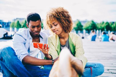 Koyu tenli kaç aşk Cafe için seçme içinde birlikte açık havada, erkek ve kadın arkadaş sosyal ağlardan Meydanı'nda dinlenme smartphone kullanarak video izlerken vakit ise öğle yemeği