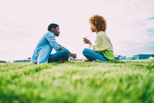 物思いにふける男女暗い皮を剥がれた友人を楽しんで話している草の上に座って休憩屋外 トレンディな服を着てアフロ アメリカ流行に敏感な自由な時間休憩一緒に会議の中の会話 — ストック写真