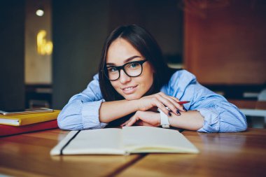 Yarım uzunluk portre şık gözlük edebiyat ile okul sırası vasıl dinlenme büyüleyici esmer öğrencinin Üniversitesi İç kitaplar. Üniversitede ders arası sırasında kameraya gülümseyen genç ve güzel kadın
