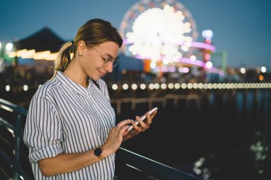 Hippi kız okuma yeni ileti showplace içinde hücresel zevk akşam eğlence gülümseyen neşeli kadın turist tatil yolu ile smartphone, ağlar eğlence parkı içinde kalan hakkında sohbet