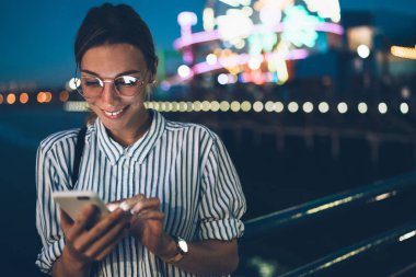 Hippi kız okuma iletisi sohbet telefon online tatil akşam eğlence parkı içinde sırasında üzerinde gülümseyen, hareket eden app gezi showplace tarama için mutlu kadın turist memnun