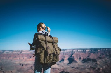 Kadın uzun yürüyüşe çıkan kimse cep telefonu mobil ağ bağlantısını kontrol tutmak sırt çantası ile arkadan görünüm keşfetmek büyük kanyon, kız yolculuk tutkusu okuma yeni mesaj dolaşımını kullanma telefon arkadaş