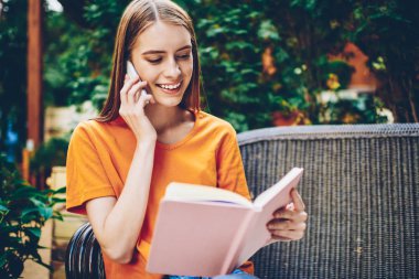 Bankta ders kitabı ücretsiz vakit gelen arkadaşıma ev ödevi bilgi dikte neşeli sarışın genç kadın. Günlüğü okuma ve telefon görüşmesinde smartphone aygıt üzerinde konuşuyor gülümseyen öğrenci