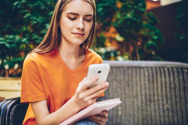 Uygulama yükleme ve favori kitap ile bankta oturan süre sosyal ağlar üzerinde cep telefonu kısa mesaj gönderme güzel öğrenci resim kırpılmış. Kopyalama alanı alanı reklam için