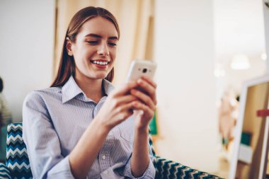 Eğitim webinar Web sitesinde smartphone içinde izlerken olumlu genç kadın internet'e bağlı. Web sitesi ve güncelleştirme Internet paylaşımı neşeli kadın blogger cep telefonunuzda multimedya mesajları