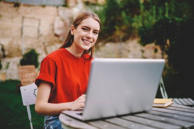 Açık havada oturma modern netbook aygıt Web sitesinde yeni grafik geliştirmeye çalışan başarılı kadın tasarımcı yarım uzunluk portre kameraya gülümseyen süre kablosuz Internet bağlantısı