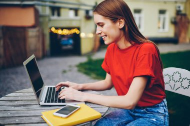 Mutlu metin yazarı metin bilgileri Internet Web sitesinde yayımlama için dizüstü bilgisayar aygıtının klavye yazarak yan görünüm. Başarılı öğrenci ilişkin fikir edinmek için ortak ders netbook açık havada hakkında sohbet