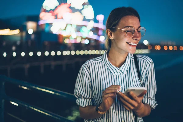 Holding cep telefonu sohbet için gülerek mutlu bir genç kadın ile Santa monica pier sonlarında gece, neşeli hippi kız eğlence parkı olan cellula holding dinlenme tatil seyahat zevk heyecan