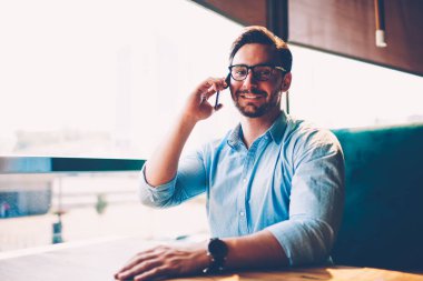 Yarım uzunluk portre pozitif erkek kafeterya şık Eyewear mobil faydaları telefonla iş bilgi için kopyalama alanı alanı yakınındaki kamera bakarken dolaşım içinde söz sahibi