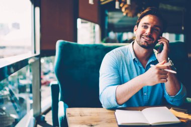 Yakışıklı sakallı adam 30 yaşında kendi srartup Proje tanıtım alanının yakınında için iş stratejisi oluşturma konusunda uzaktan çalışırken arkadaşça mobil sohbet sırasında yeni fikir ayrıntılarını tartışıyor